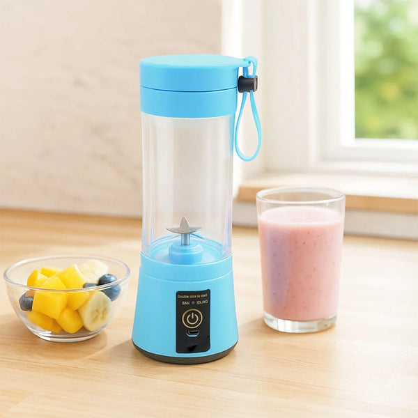 Blue portable blender with a glass of pink smoothie on a wooden table.