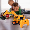 Toy excavator with remote control in front of a child playing with toys in the background