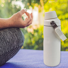 White insulated bottle with a person meditating outdoors