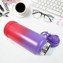 Gradient pink to purple water bottle on a desk with coffee, glasses, and keyboard.