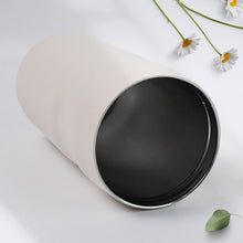 White mug with black interior on a light surface with flowers