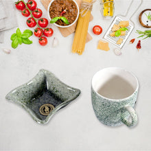 Speckled ceramic dish and mug on a light surface with ingredients in the background