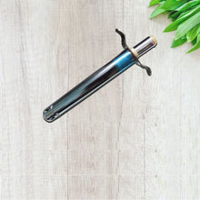 Metallic sword on a light wooden surface with green leaves in the corner