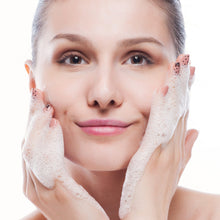 Woman washing her face with a sponge on a white background