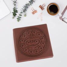 Chocolate Oreo cookie with a cup of coffee and office supplies on a white surface
