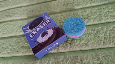 Oreo cookie-shaped eraser with packaging on a green wooden surface