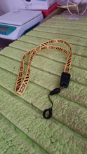 Orange and black lanyard with a clip on a green surface