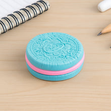 Blue and pink circular object resembling an Oreo cookie on a wooden surface.
