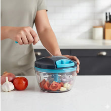 Person using a hand-held food chopper with vegetables on a kitchen counter