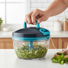 Hand holding a kitchen chopper with chopped vegetables in a kitchen setting