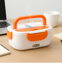 Electric lunch box with orange handle on a desk with laptop and mug