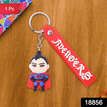 Superman keychain with red band featuring 'Avengers' on a wooden surface