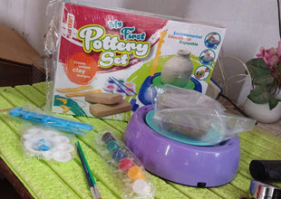 Children's pottery set with a box labeled 'My First Pottery Set' on a green surface.