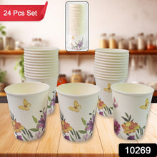 Set of paper cups with floral design on a wooden surface, with stacks in the background.