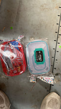 Two small plastic containers with lids on a concrete floor.