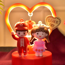 Two figurines of a boy and girl with a heart-shaped light in the background