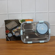Clear food container with blue lid next to its packaging on a wooden surface.