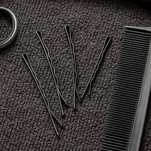 Set of black hairpins and a comb on a textured gray surface