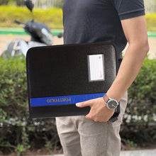 Person holding a black portfolio with a blue band outdoors