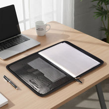 Laptop on a wooden desk with a folder, pen, and mug in a home office setting.