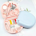 Pink sewing kit with scissors, thread, and other tools on a white background