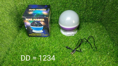 Projection lamp with packaging and USB cable on grass, with text 'DD = 1234' overlayed.