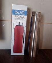 Silver water bottle next to its packaging on a wooden surface.