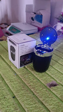 Black and blue electronic device with a glowing blue light on a green surface.
