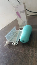 Turquoise handheld device with packaging and instructions on a wooden surface