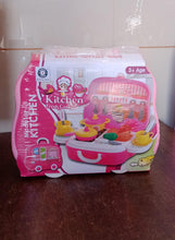 Toy kitchen set in packaging on a wooden surface with tiled wall background