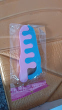 Pink and blue comb in clear packaging on a textured surface