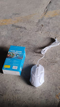 White computer mouse with cable on a concrete surface next to its packaging